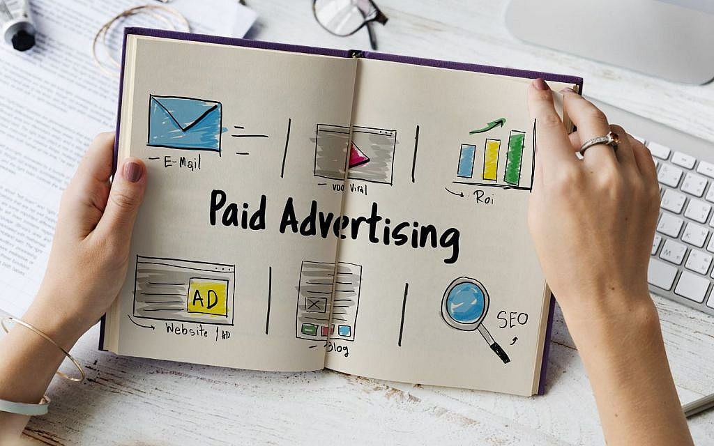 Media buyer reviewing ad spend and return figures on two monitors